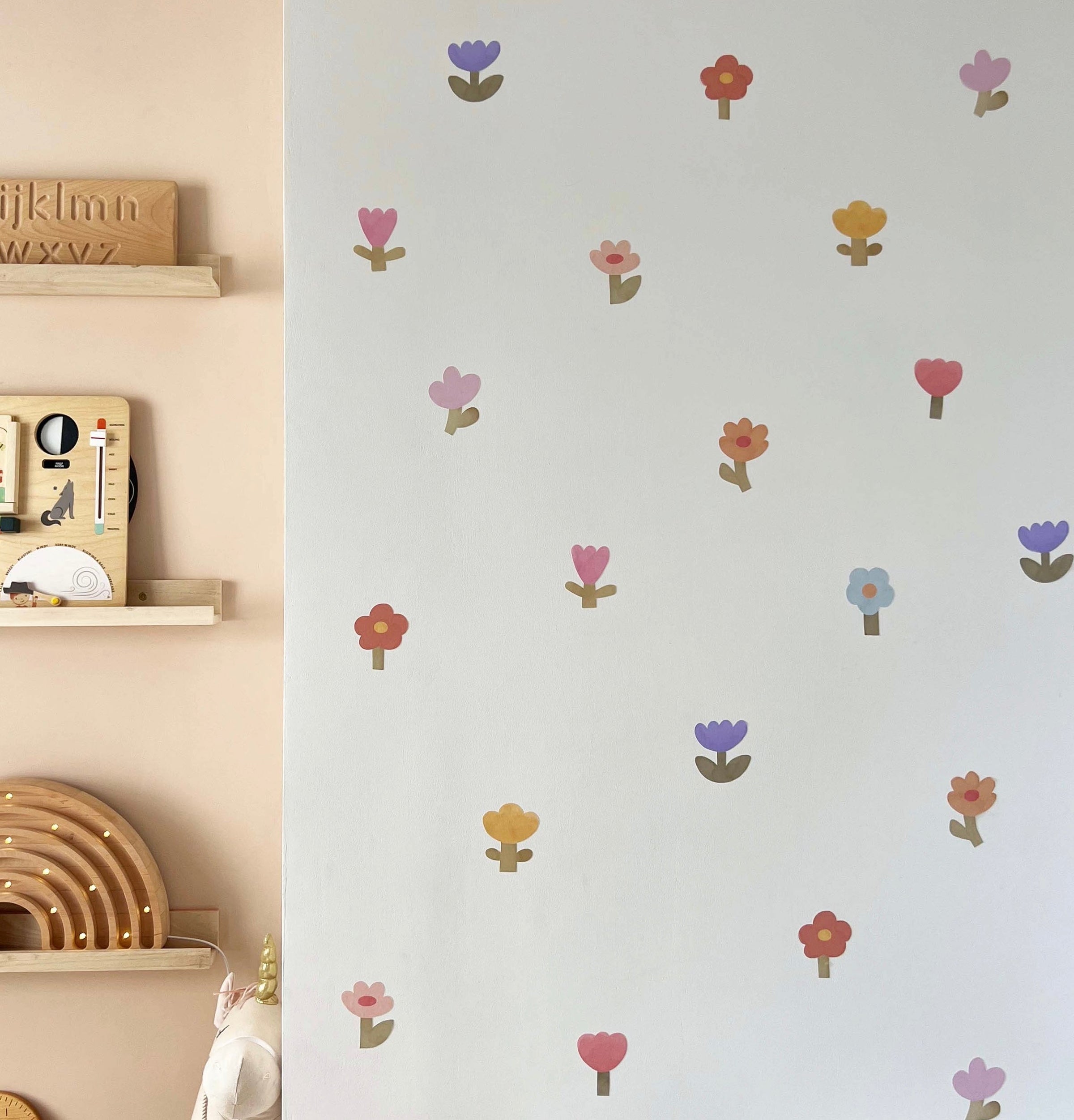 Removable fabric wall stickers from Kid of the Village displayed in a child’s bedroom with colourful flower decals on the wall.